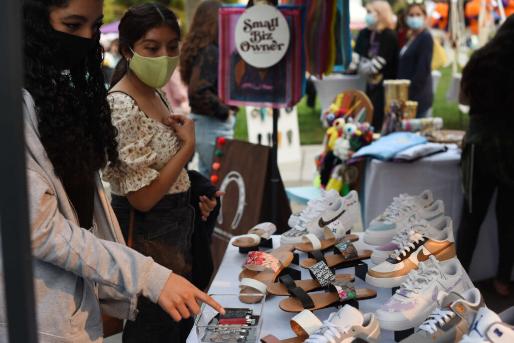 Shoppers check out the handmade lighter cases and an assortment of customized footwear by Miguel Martin, 18, owner of Martin Kickzz, during The SoCo Market held in Old Courthouse Square in downtown Santa Rosa on Friday, Aug. 20, 2021. (Erik Castro/for The Press Democrat)