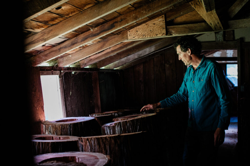 Michael Thiele in a barn filled with logs that will eventually become home to "feral" honeybees at the Apis Arborea headquarters in Sebastopol. TreeNests are built there before being installed in trees. (Eileen Roche)