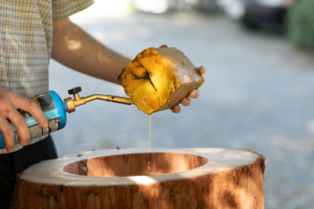 Apis Arborea conservation specialist Conner McElroy uses a blowtorch to melt beeswax into a log that will be used as a TreeNest. Beeswax contains propolis, which attracts bees to come make a home there. (Eileen Roche)