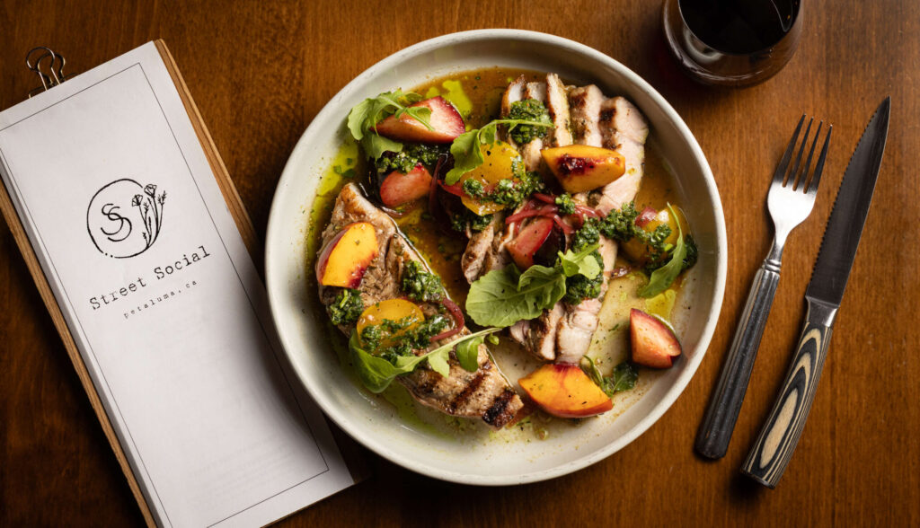 Grilled Pork Porterhouse with au jus and local stone fruit from Street Social Thursday, August 14, 2025 in Petaluma. (John Burgess / Press Democrat)