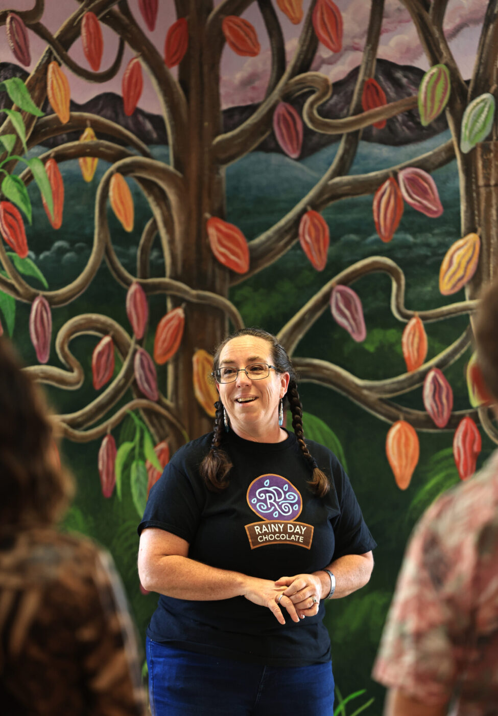 Jennifer Daly, co-owner and CEO of Rainy Day Chocolate in Forestville, Sunday, March 29, 2026. The mural in the background is a cacao tree. (Kent Porter / The Press Democrat)