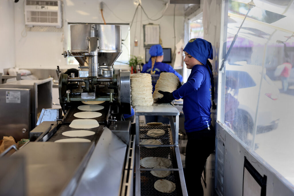 Polette Mejia Quiroz, 15, moves a stack of freshly made tortillas at Tortilleria Apatzingan in Santa Rosa Tuesday, July 8, 2025. (Beth Schlanker / The Press Democrat)