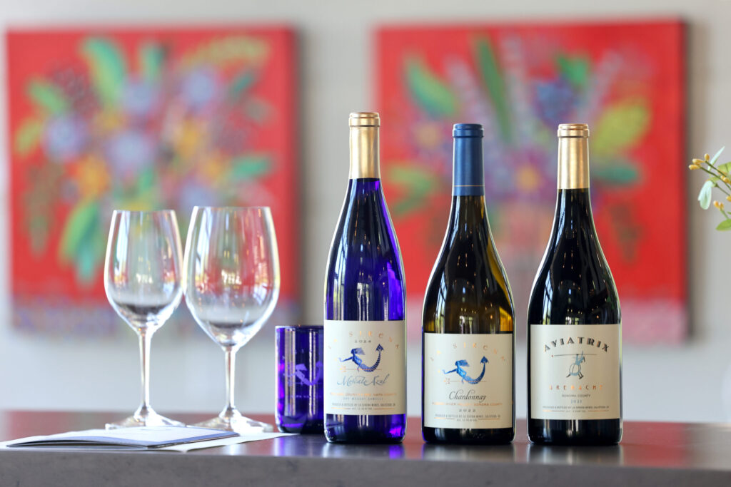 (From left) Bottles of La Sirena Moscato Azul, La Sirena Chardonnay, and Aviatrix Grenache at La Sirena tasting room in Calistoga Wednesday, May 13, 2026. (Beth Schlanker / The Press Democrat)