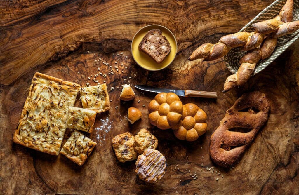 Various breads from local businesses, including, clockwise from left, focaccia from Pastasciutta, toast from Quail & Condor, baguette from Sarmentine, fougasse from Goguette, Parker House rolls from Bijou and scones from Nightingale Breads. (John Burgess / The Press Democrat)