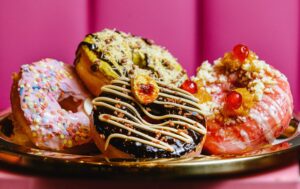 A selection of specialty doughnuts from SoCo Dough Co. inside the Graton Casino & Resort, clockwise from bottom, Gone Bananas, Pretty in Pink, Dubai of My Eye and Right Side Up Friday, May 29, 2026 in Rohnert Park. (John Burgess/The Press Democrat)