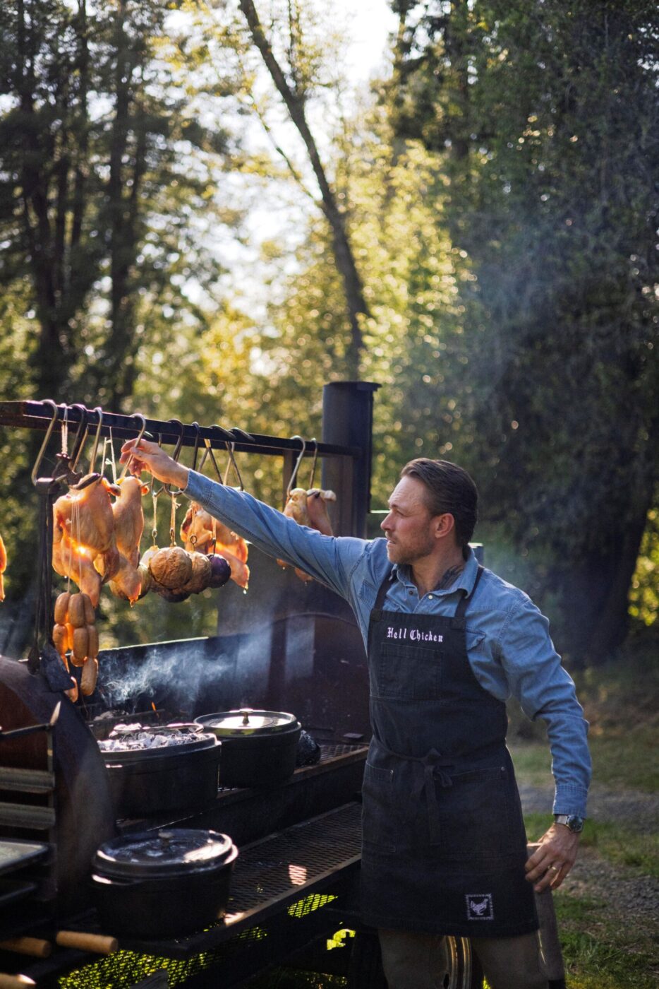 Chef Lee Desrosiers slow-roasts whole chicken above hot embers in his west county field kitchen. (Conor Hagen)