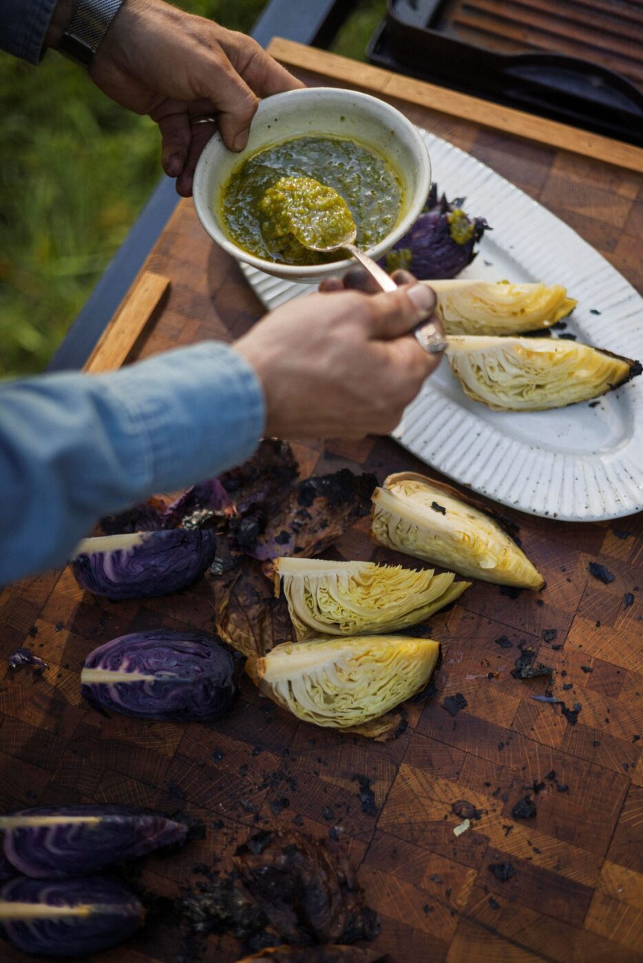 Lee Desrosiers spoons a spicy, tangy sauce made with chiles and limes over cabbage he slow-roasted over coals. (Conor Hagen)