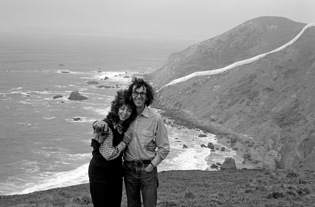 Jeanne-Claude and Christo standing before Running Fence’s entry into the Pacific Ocean. (Morrie Camhi / Copyright Christo and Jeanne-Claude Foundation)