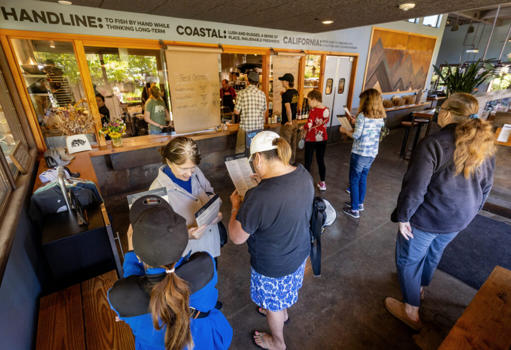 Customers search the extensive menu before ordering at the window at Handline Thursday, July 9, 2026 in Sebastopol. (John Burgess/The Press Democrat)