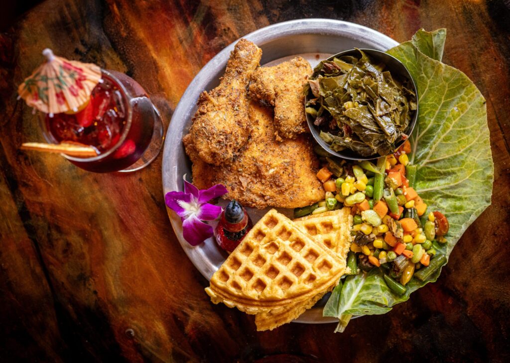 Buttermilk Fried Chicken with collard greens, succotash cornbread waffle and crack butter with a Hibiscus Flower N/A cocktail from Saucy Mama’s Jook Joint Friday, July 18, 2026 in Guerneville. (John Burgess/The Press Democrat)
