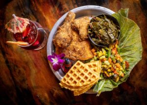 Buttermilk Fried Chicken with collard greens, succotash cornbread waffle and crack butter with a Hibiscus Flower N/A cocktail from Saucy Mama’s Jook Joint Friday, July 18, 2026 in Guerneville. (John Burgess/The Press Democrat)