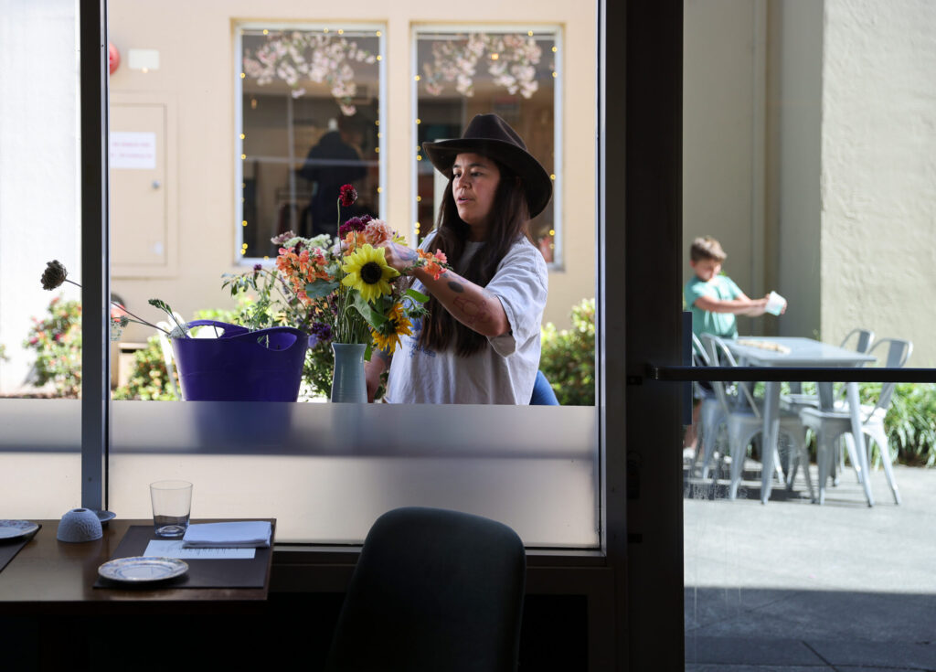Melissa McGaughey arranges flowers before the dinner service at Troubadour Bread & Bistro in Healdsburg on Thursday, July 2, 2026. (Christopher Chung/The Press Democrat)