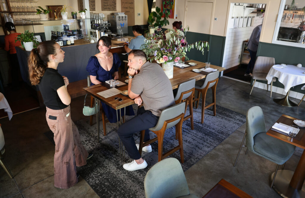 Server Elli McRae, left, talks with diners Jillian and Luca Castaldo at Troubadour Bread & Bistro in Healdsburg on Thursday, July 2, 2026. (Christopher Chung/The Press Democrat)