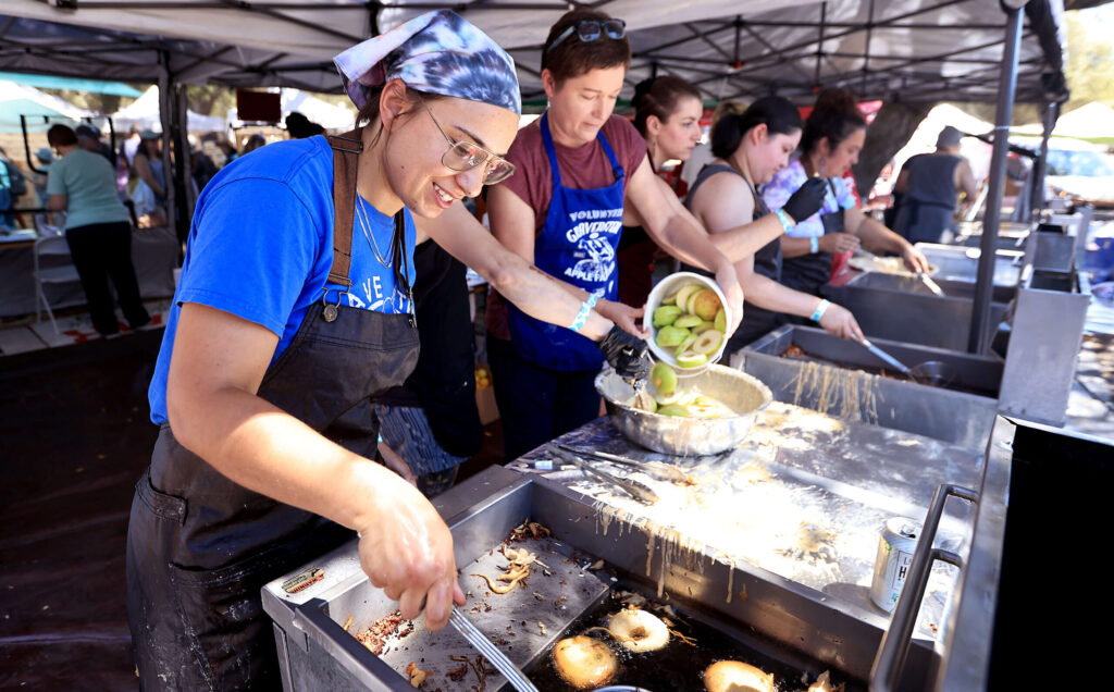Sasha Rusthmeyer, left, and Leah Redon join their North Bay Derby (roller derby) teammates in making apple fritters during the Gravenstein Apple Fair in Sebastopol, Saturday, August 9, 2025. (Kent Porter / The Press Democrat)