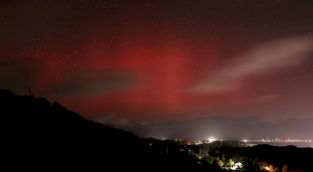The aurora borealis makes a low latitude dip over Lake County. The community lights of Lakeport, foreground middle, with Nice and Lucerne in the distance, right, serve as artificial contrast to nature's light show. Photo taken from the Hopland Grade with a 30 second exposure, Thursday, March 23, 2023. (Kent Porter / The Press Democrat)