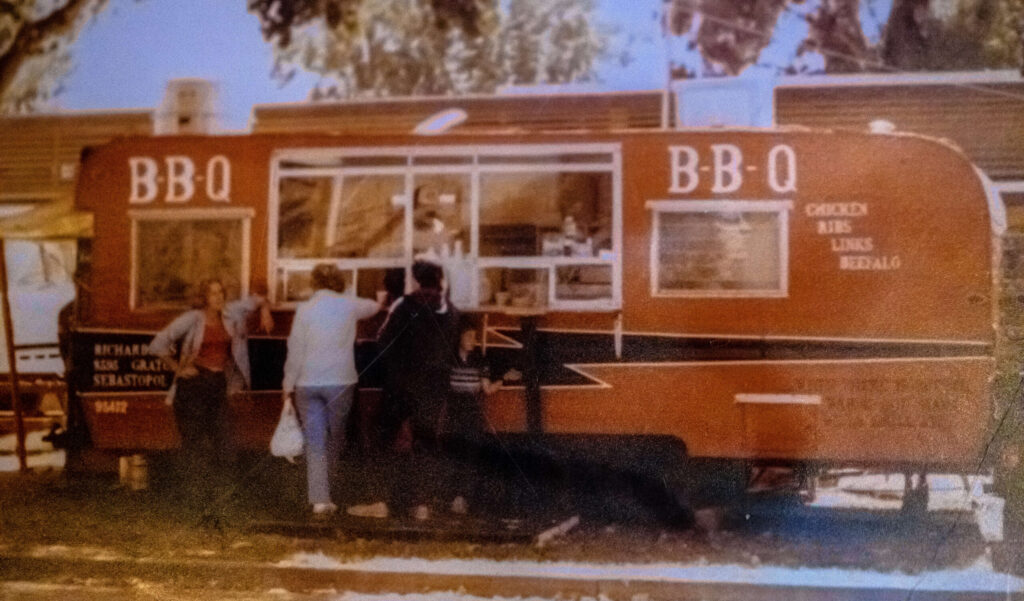 A photo of Yvette Bidegain’s parents trailer, from when they first started out at the Sonoma County fair, hangs at her barbecue spot Saucy Mama’s in Guerneville, Wednesday June 12, 2024. (Chad Surmick / The Press Democrat)