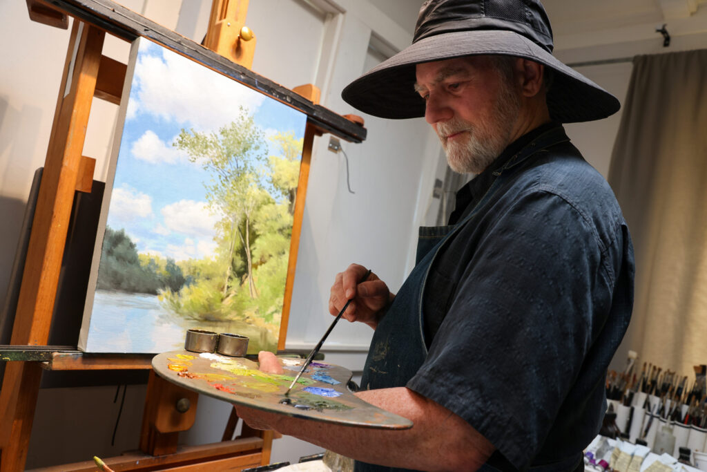 Christopher Leith Evans works on a painting of a nearby scene of the Russian River at his home studio in Healdsburg on Monday, May 11, 2026. (Christopher Chung/The Press Democrat)