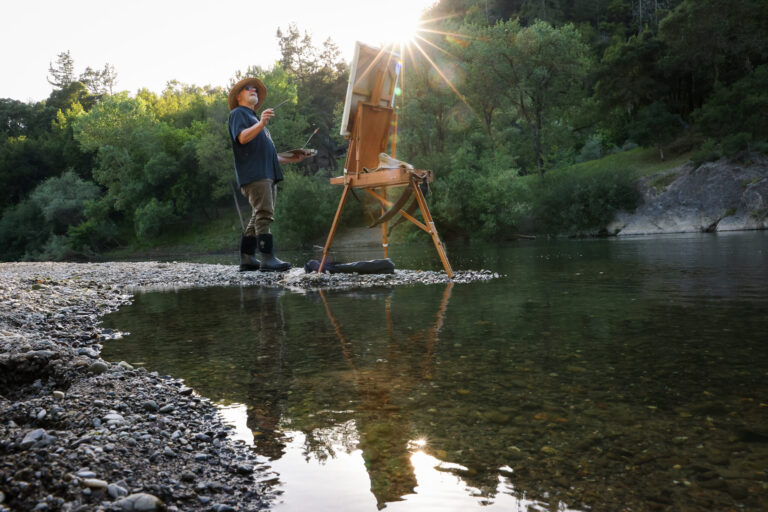 Christopher Leith Evans paints a scene along the Russian River as the sun begins to set near his home in Healdsburg on Monday, May 11, 2026. (Christopher Chung/The Press Democrat)
