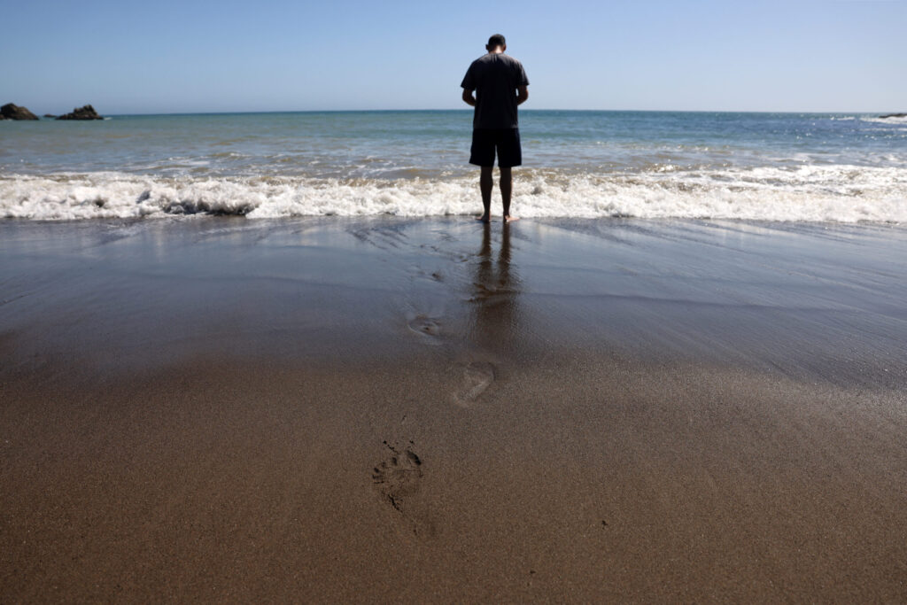 A Camino de Sonoma hiker take a moment of reprieve at the beach in Fort Ross Tuesday, May 19, 2026. (Beth Schlanker / The Press Democrat)
