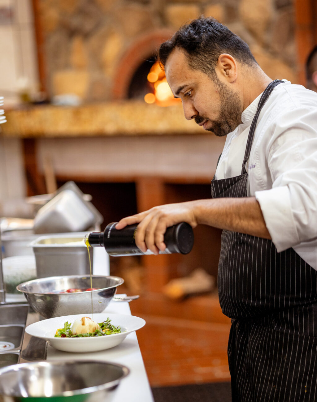 Owner/chef Baki Bekci finishes a Burrata Salad with olive oil in the kitchen at Capriciano Osteria Thursday, July 30, 2026 in Santa Rosa. (John Burgess/The Press Democrat)