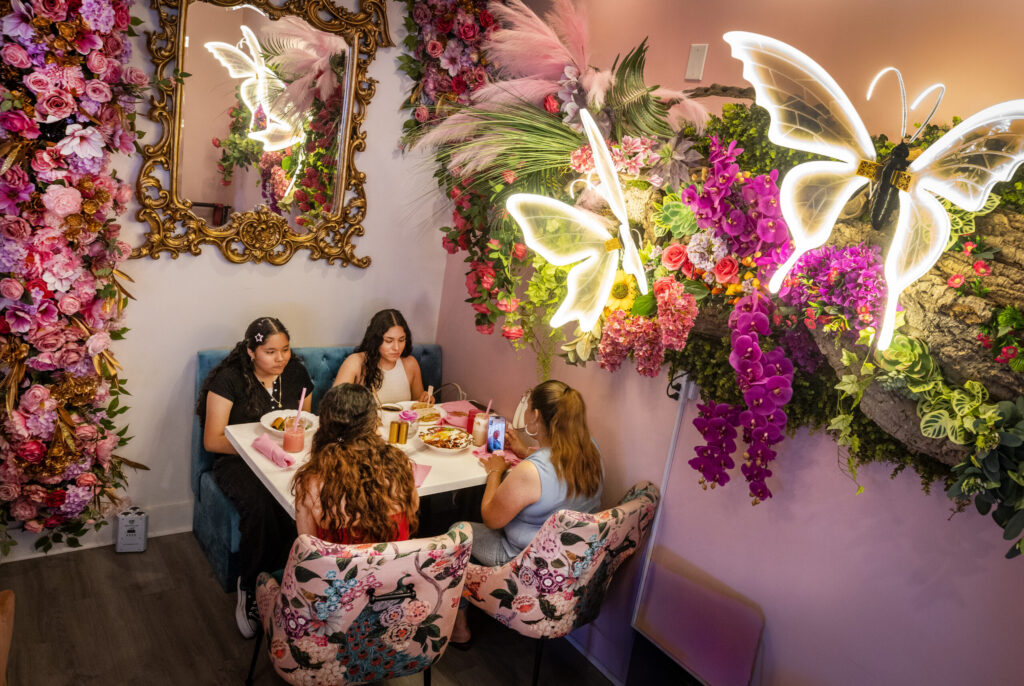 Eating among the walls of imitation flowers and lights from Café Carrusel Tuesday, July 28, 2026 in Santa Rosa. (John Burgess/The Press Democrat)