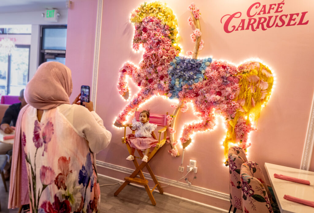 Sumiya Ahmed, of Santa Rosa and Dubai, takes a photo of her daughter Issa, 1, in front of the glowing flower horse at Café Carrusel Tuesday, July 28, 2026 in Santa Rosa. (John Burgess/The Press Democrat)