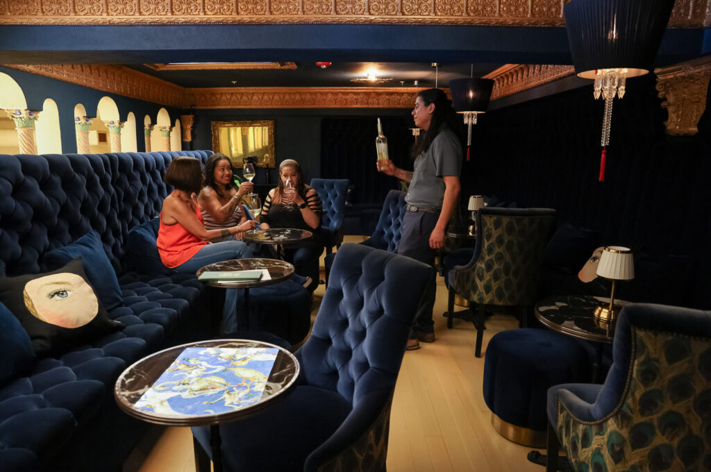 Wine educator Pedro Acosta, right, serves wine to Stephanie Wargo, Juli Horne, and Dawn Harris in the mezzanine lounge at Flora Springs Wine Lounge in Napa on Friday, August 21, 2026. (Christopher Chung/The Press Democrat)