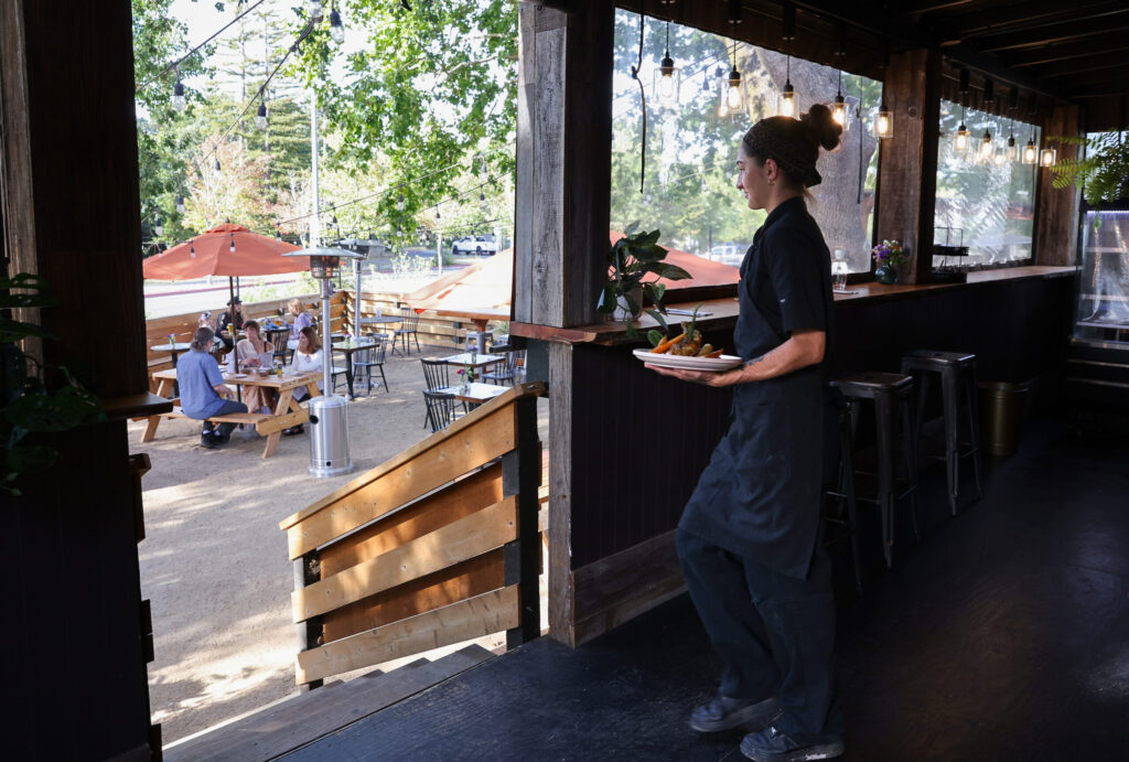 Dunia Khallouf brings out a dish to customers at The Porch Kitchen in Sebastopol on Thursday, August 20, 2026. (Christopher Chung/The Press Democrat)