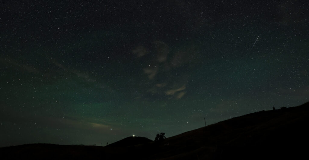 A Perseid meteor, right, dots the morning sky, Thursday, August 13, 2026. The Perseid’s are remnants of comet 109P/Swift-Tuttle and will active until August 24. Geyser Peak, above Alexander Valley, is in the distance with a hint of the northern lights. (Kent Porter / The Press Democrat)