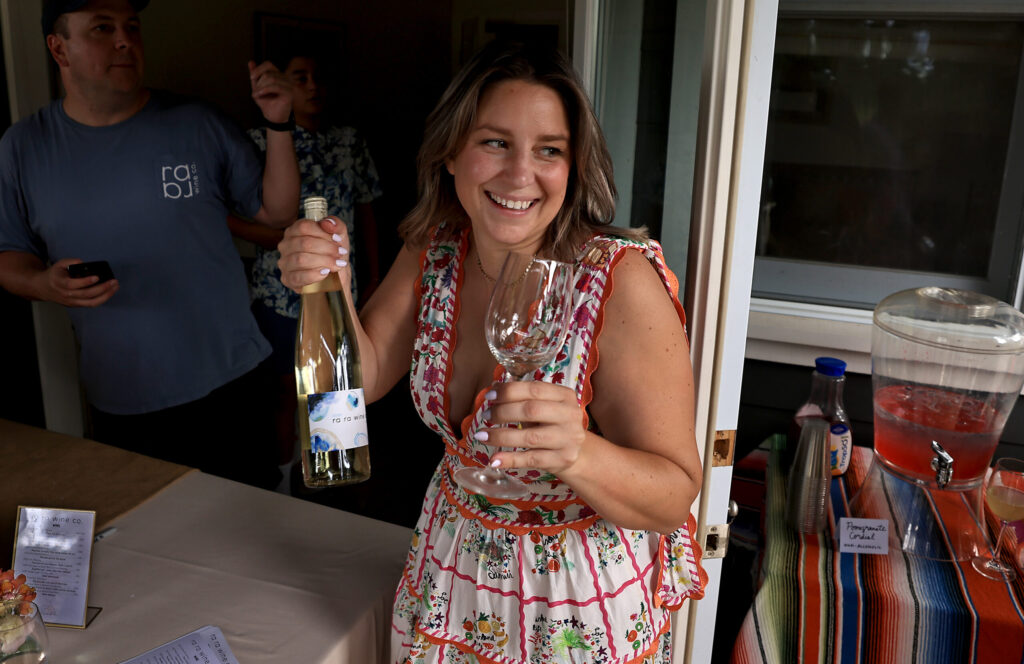 Kara Groom prepares to give a bottle of her label RaRa Wines to a friend, Saturday, July 11, 2026, during a party for family, friends and her wine club members, Saturday, July 11, 2026, in Healdsburg. (Kent Porter / The Press Democrat)
