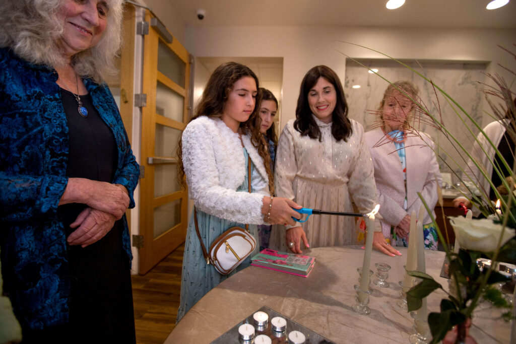 Mia Dotan, 11, lights a candle next to her twin sister, Ella Dotan, as Co-director Altie Wolvovsky, center, conducts the lighting while Linda Emblen of Santa Rosa, left, and Linda Blum of Sebastopol, right, looks on as women and girls light candles before sunset to usher in Rosh Hashanah at Sonoma County Chabad Jewish Center, Friday, September 15, in Santa Rosa. (Darryl Bush / For The Press Democrat)